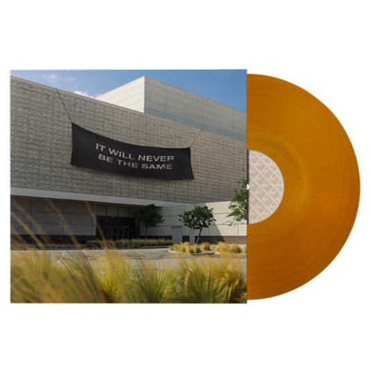Orange vinyl record album against a backdrop of a modern building with a banner.