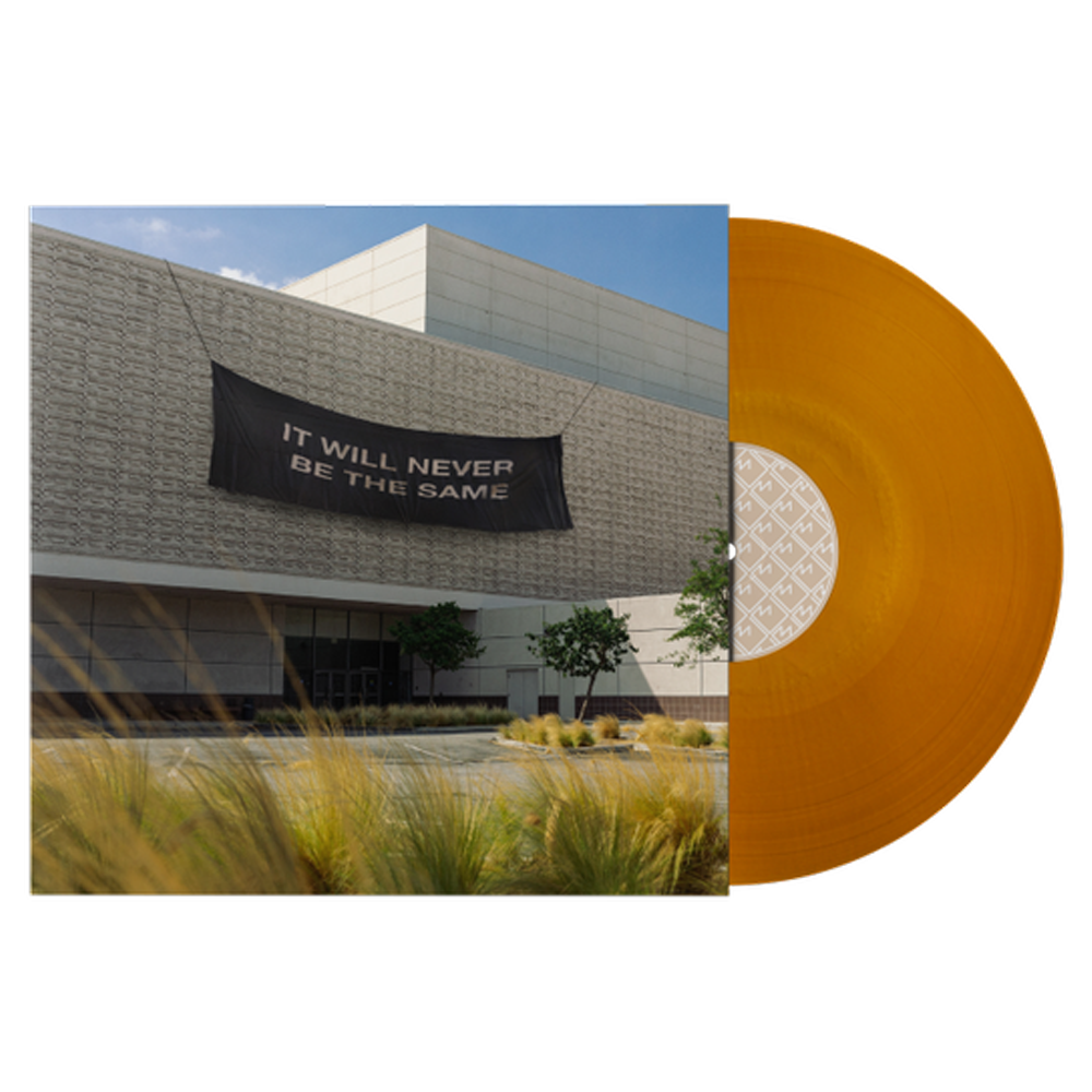 Orange vinyl record album against a backdrop of a modern building with a banner.